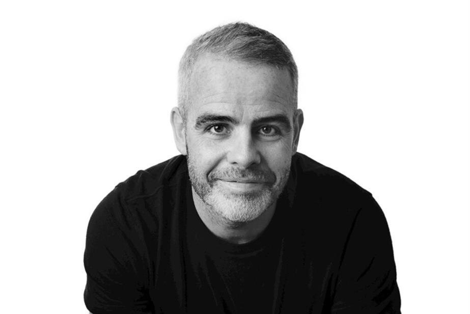 A black and white pic of Andy Freeman, smiling into the camera, against a white backdrop