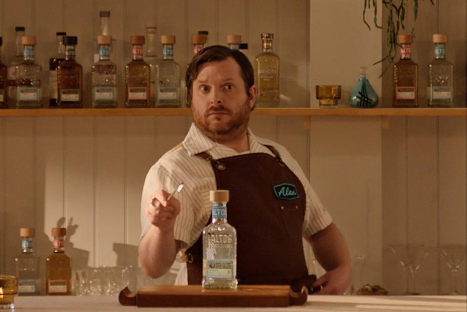 A man standing behind a bottle of tequila