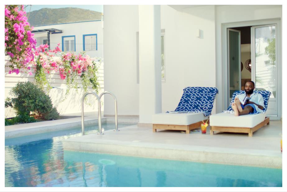 A man sits in a sun lounger by a swimming pool