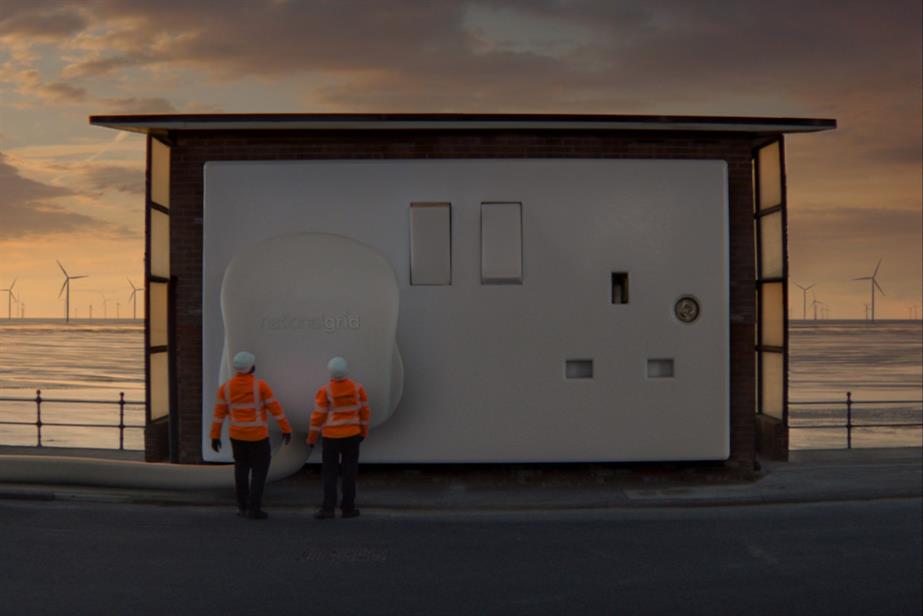 Still from ad showing a giant power plug being plugged in with a wind farm in the background